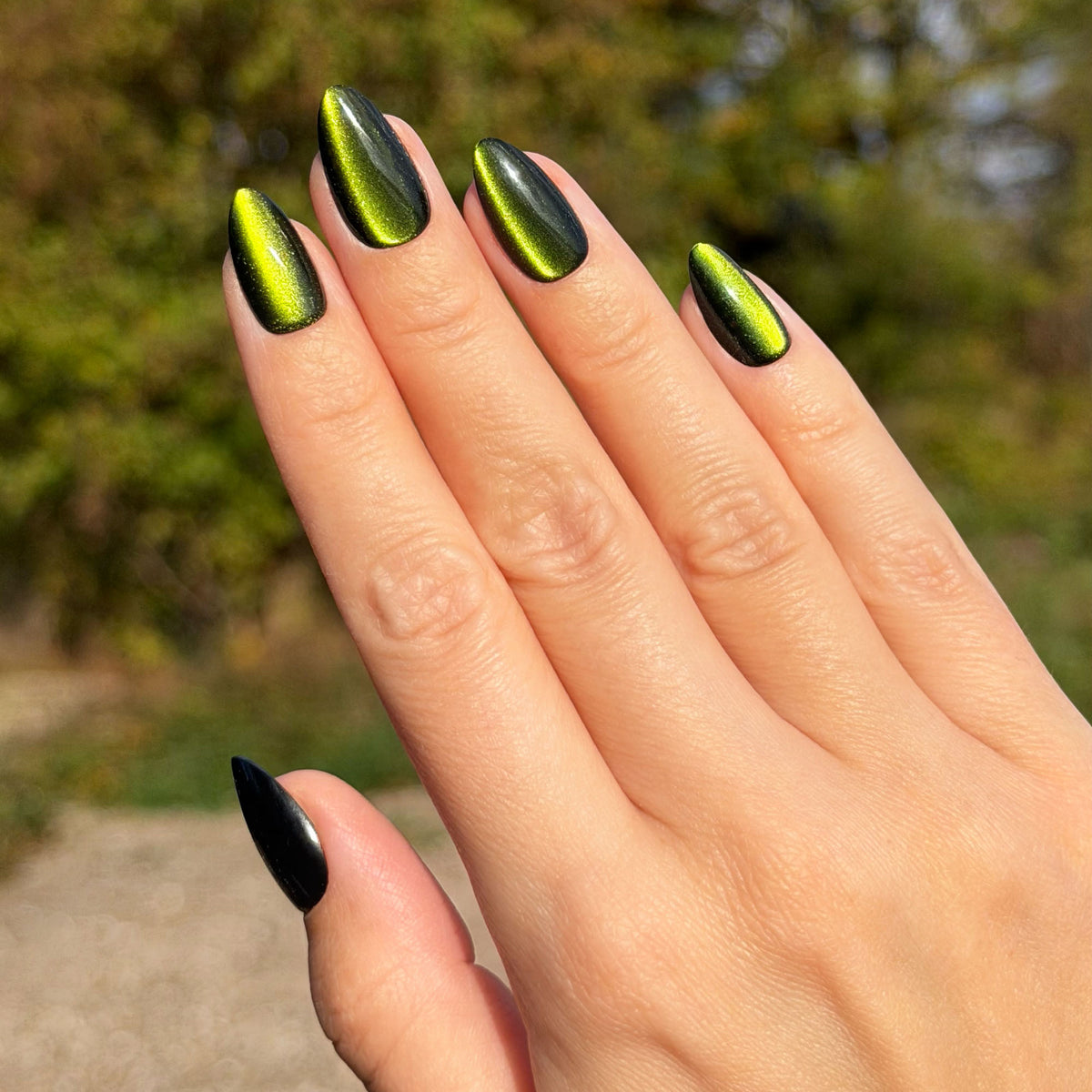 Hand in schräger Ansicht mit Soft Gel Press-On Nails „Matcha“ in Dunkelgrün mit Schimmereffekt, kurz und mandelförmig.