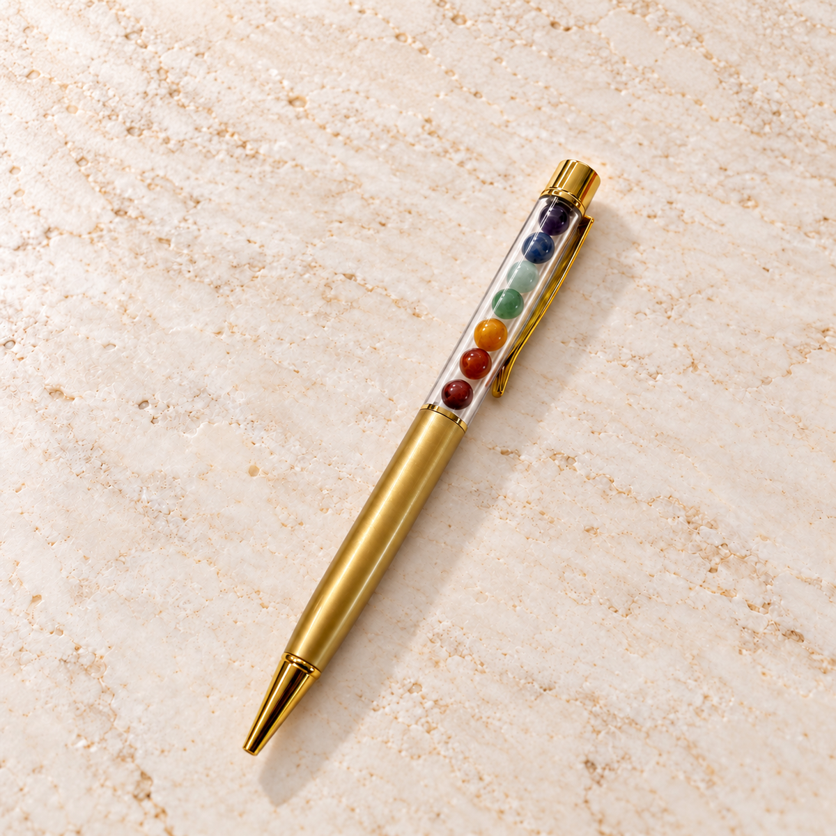 Chakra Edelstein-Kugelschreiber Gold auf heller Marmorfläche