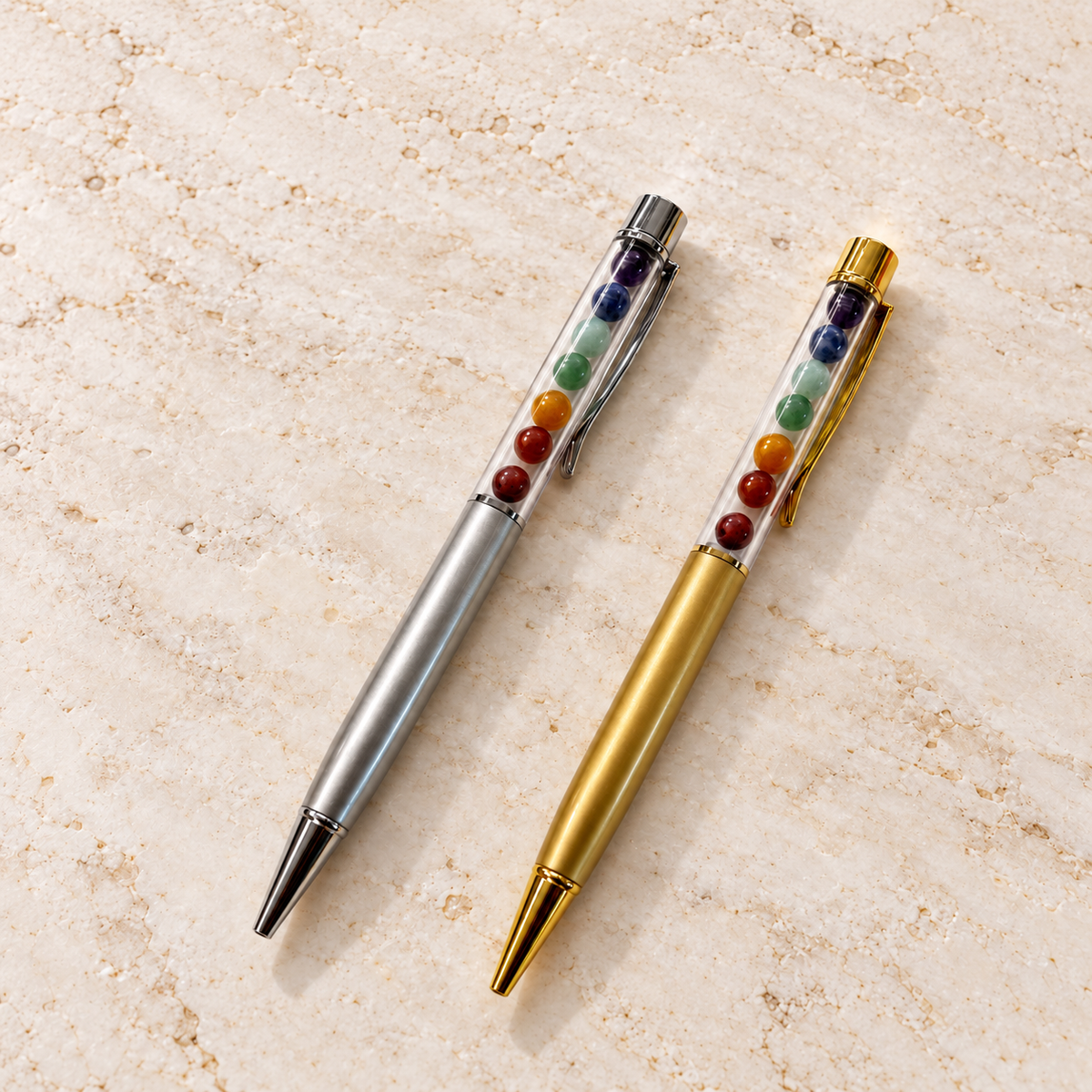 Chakra Edelstein-Kugelschreiber Gold und Silber auf heller Marmorfläche