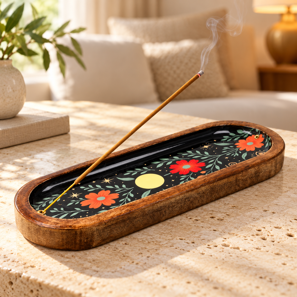 Räucherstäbchenhalter aus Mangoholz mit schwarzem Blumenmotiv und rauchendem Stäbchen auf hellem Couchtisch im gemütlichen Wohnzimmer